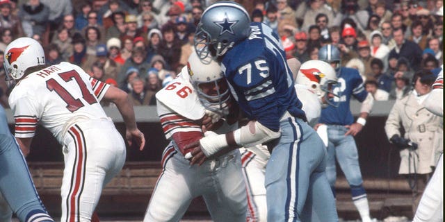 Jethro Pugh #75 de los Dallas Cowboys corre contra Conrad Dobler #66 de los St. Louis Cardinals durante un partido de fútbol americano de la NFL el 3 de diciembre de 1972 en el Busch Stadium en St. Louis, Missouri.  Pugh jugó para los Vaqueros de 1965 a 1978.