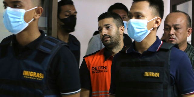 Immigration officers escorted Australian fugitive Antonio Strangio, center, to a press conference in Nusa Dua, Bali, Indonesia, on Feb. 19, 2023.