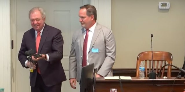 Alex Murdaugh's defense lawyer Dick Harpootlian playfully points a gun at prosecutors during a demonstration involving forensic expert Mike Sutton (right) Feb. 21 in Walterboro, South Carolina.
