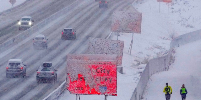 Runners negotiate snow covered paths along Interstate 80 in Salt Lake City on Wednesday, Feb. 22, 2023. 