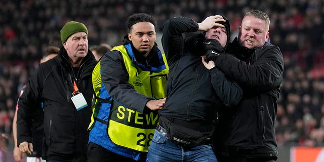 A spectator who entered the field during a UEFA Europa League match between PSV and Sevilla at the Philips Stadium Feb. 23, 2023, in Eindhoven, Netherlands, is escorted off the field. 