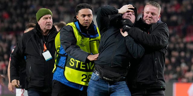 A spectator who entered the field during a UEFA Europa League match between PSV and Sevilla at the Philips Stadium Feb. 23, 2023, in Eindhoven, Netherlands, is escorted off the field.