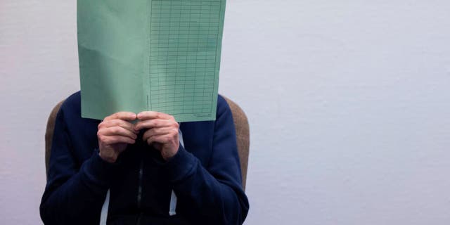 The defendant in the Wermelskirchen abuse complex holds a folder in front of his face in the courtroom in Cologne, Tuesday, Feb. 28, 2023.