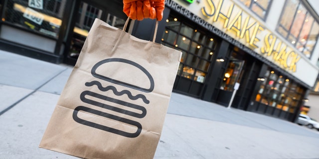 A person wearing a protective glove holds a bag outside Shake Shack during the coronavirus pandemic on April 20, 2020, in New York City.