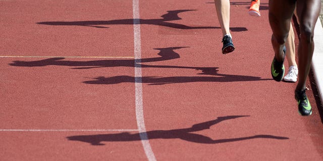 Las sombras de los corredores en la final de una milla se dibujan en la pista de atletismo.