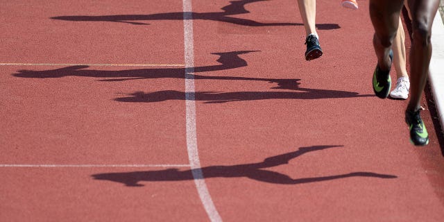 Las sombras de los corredores en la final de una milla se dibujan en la pista de atletismo.