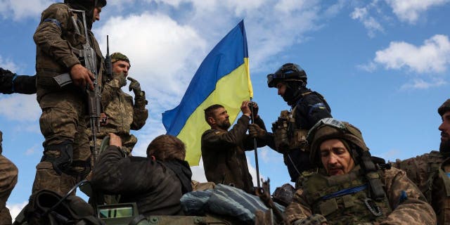 Amasosha ase-Ukraine alungisa ifulegi lezwe phezu kwesiphathi sezisebenzi esihlomile emgwaqeni eduze kwase-Lyman, esifundeni sase-Donetsk ngo-Oct. 4, 2022.