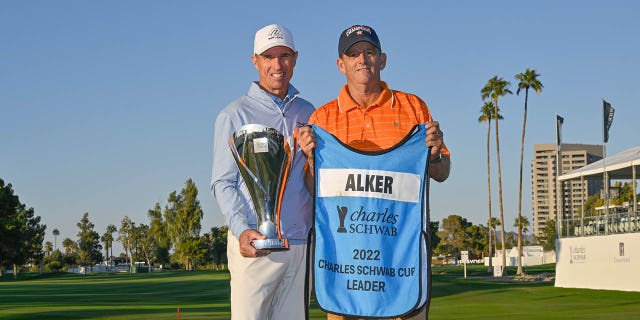 Steven Alker, of New Zealand, and his caddie Sam Workman, right, hold the Charles Schwab Cup on the 18th green after the final round of the PGA TOUR Champions Charles Schwab Cup Championship at Phoenix Country Club on Nov. 13, 2022 in Phoenix.