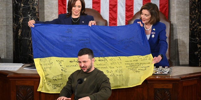 Ukraine's President Volodymyr Zelensky addresses the US Congress as US Vice President Kamala Harris and US House Speaker Nancy Pelosi, D-Calif., hold a Ukrainian national flag that Zelensky gave them at the US Capitol in Washington, DC on December 21, 2022.