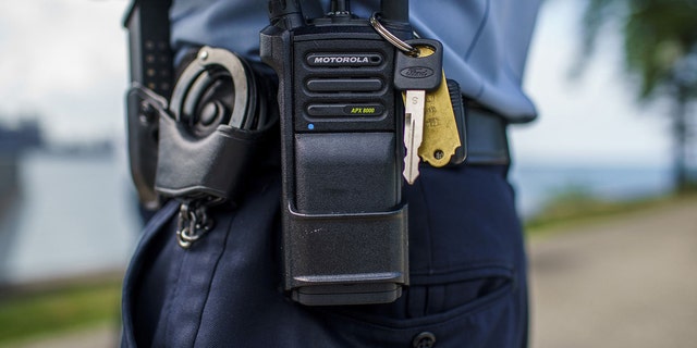 Un officier de police de Chicago se tient avec une radio de police près d'Oak Street Beach le 18 août à Chicago.