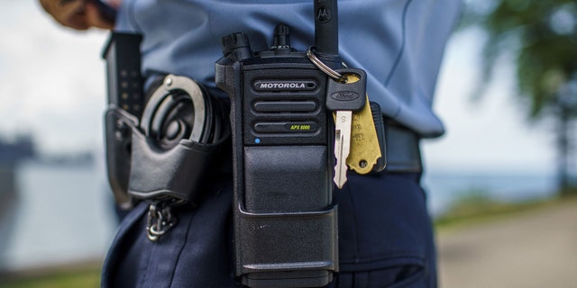 A Chicago police officer stands with a police radio near Oak Street Beach on Aug. 18 in Chicago.