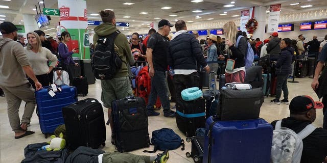 Travellers line up to check their Sunwing airline flights at terminal 2 of Cancun international airport in Cancun, Quintana Roo state, Mexico, on December 27, 2022.