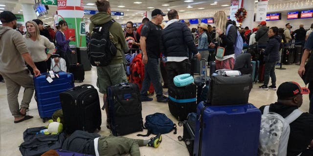 Travellers line up to check their Sunwing airline flights at terminal 2 of Cancun international airport in Cancun, Quintana Roo state, Mexico, on December 27, 2022.