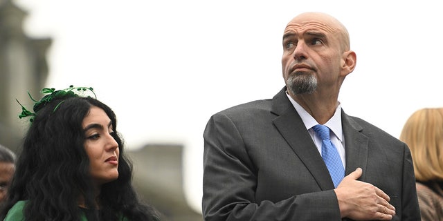 U.S. Senator John Fetterman (D-PA) and his wife, Gisele Barreto Fetterman, stand during the singing of the National Anthem before Josh Shapiro is sworn in as Governor of Pennsylvania at the State Capitol Building on January 17, 2023 in Harrisburg, Pennsylvania. Shapiro defeated Republican nominee Doug Mastriano by nearly 15 percent in the November election. (Photo by Mark Makela/Getty Images)