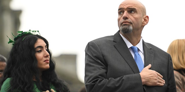 U.S. Senator John Fetterman (D-PA) and his wife, Gisele Barreto Fetterman, stand during the singing of the National Anthem before Josh Shapiro is sworn in as Governor of Pennsylvania at the State Capitol Building on January 17, 2023 in Harrisburg, Pennsylvania. Shapiro defeated Republican nominee Doug Mastriano by nearly 15 percent in the November election. (Photo by Mark Makela/Getty Images)