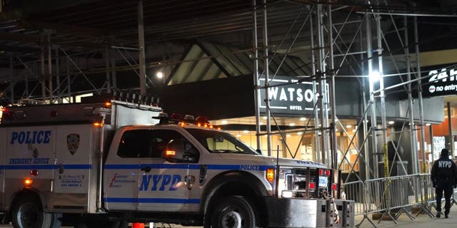 New York Police Department officers and Department of Sanitation workers clear asylum seekers from the sidewalk in front of Watson Hotel in Hell's Kitchen of Manhattan Wednesday.