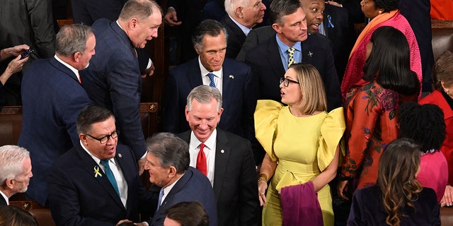 US Senator Kyrsten Sinema (C-R), (I-AZ), and Senator Mitt Romney (C L blue tie) (R-UT) arrive for US President Joe Biden's State of the Union address.