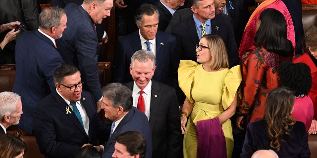 US Senator Kyrsten Sinema (C-R), (I-AZ), and Senator Mitt Romney (C L blue tie) (R-UT) arrive for US President Joe Biden's State of the Union address.
