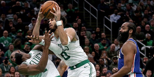 Jayson Tatum, #0 of the Boston Celtics, collides with Jaylen Brown, #7, as James Harden, #1 of the Philadelphia 76ers, looks on during the first half of an NBA game at TD Garden on February 8, 2023 in Boston.