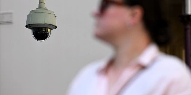 A woman walks past surveillance cameras in Melbourne on February 9, 2023. - Australia's Defense Department to remove Chinese-made surveillance cameras from its buildings to ensure they are "completely safe"the government said on Feb. 9.