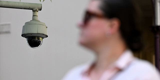 A woman walks past a security camera in Melbourne on February 9, 2023. - Australia's defence department will strip its buildings of Chinese-made security cameras to ensure they are