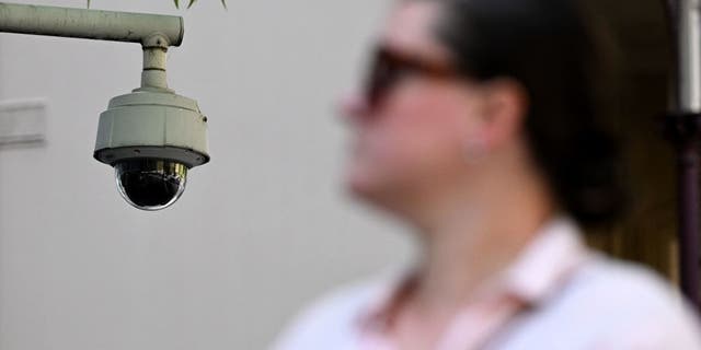 A woman walks past a security camera in Melbourne on February 9, 2023. - Australia's defence department will strip its buildings of Chinese-made security cameras to ensure they are "completely secure", the government said on February 9.