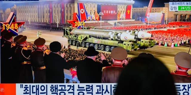 A pair of ICBM launchers pass by crowds in Pyongyang. 