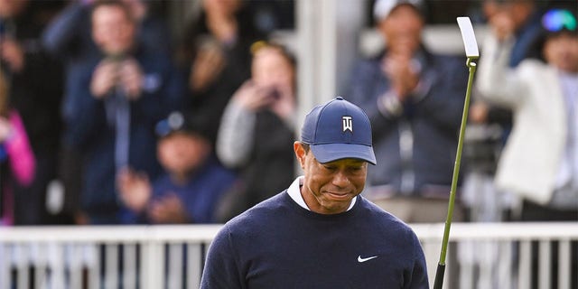 Tiger Woods smiles and raises his putter after making a birdie putt on the 17th hole green during the first round of the Genesis Invitational on Feb. 16, 2023.