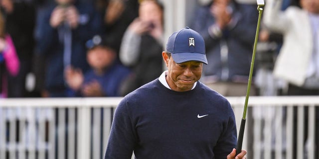 Tiger Woods smiles and raises his putter after making a birdie putt on the 17th green during the first round of the Genesis Invitational on February 16, 2023.