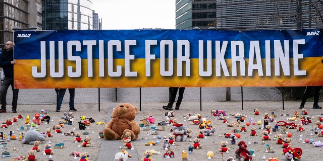 People from U.S.-based nonprofit organization avaaz light candles beside teddy bear in Schuman Roundabout, the heart of the EU district on February 24, 2023 in Brussels, Belgium. 