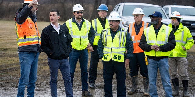 Secretary of Transportation Pete Buttigieg, second left, visits investigators on Feb. 23, 2023, at the site of the recent train derailment in East Palestine, Ohio.