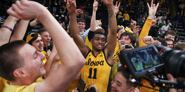 El guardia de los Iowa Hawkeyes, Tony Perkins #11, celebra con la sección de estudiantes después de la victoria en tiempo extra sobre los Michigan State Spartans en Carver-Hawkeye Arena, el 25 de febrero de 2023, en Iowa City, Iowa.  