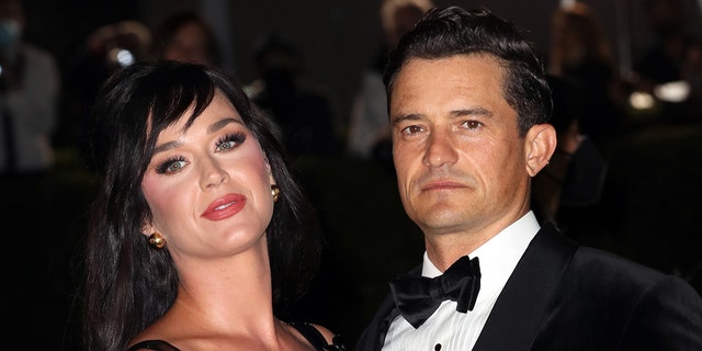 Katy Perry in a black dress with her head tilted back and Orlando Bloom in a black tuxedo at The Academy Museum of Motion Pictures Opening Gala in Los Angeles