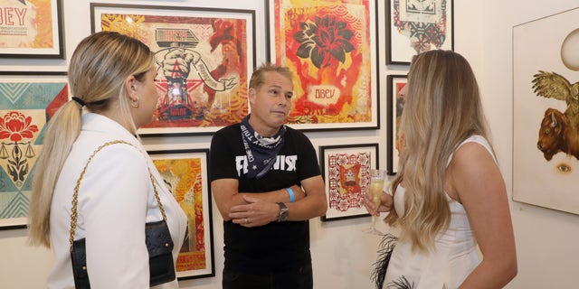 MIAMI, FLORIDA - NOVEMBER 30: Artist Shepard Fairey (C) talks with Renni Korniloff and Miranda Korniloff at Art Miami + Context Art Miami VIP Previews on November 30, 2021 in Miami, Florida. (Photo by Aaron Davidson/Getty Images for Art Miami + Context Art Miami)