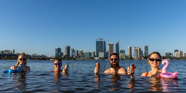 Sarah Jackson, Sam Lowe, Lachlan Alexander and Monica Lewis enjoy a drink and swim in the Swan River in South Perth on January 22, 2022 in Perth, Australia. 