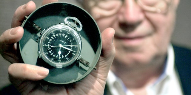Theodore Van Kirk, the flight navigator aboard the Enola Gay, held up the navigator's master clock he carried during the atomic bomb mission over Hiroshima. 