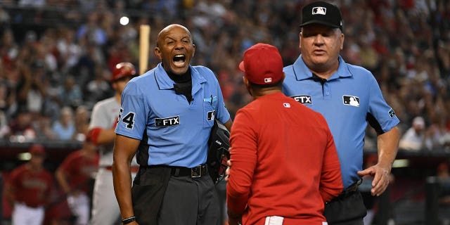 Third base umpire Jeff Nelson, right, steps in between manager Oliver Marmol of the St. Louis Cardinals, center, and home plate umpire C.B. Bucknor during an argument after Marmol was ejected during the third inning of a game against the Arizona Diamondbacks at Chase Field on Aug. 21, 2022, in Phoenix.