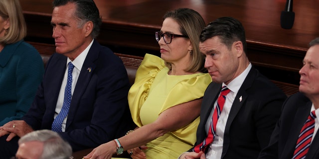 From left to right, Sen. Mitt Romney, R-Utah, Sen. Kyrsten Sinema, I-Ariz., and Sen. Todd Young, R-Ind., sit together during President Biden's State of the Union address during a joint meeting of Congress in the House Chamber of the U.S. Capitol on Feb. 7, 2023, in Washington, D.C.