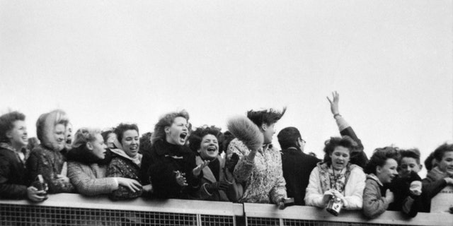 NEW YORK - FEBRUARY 7: Fans scream with excitement at the arrival of The Beatles at John F. Kennedy International Airport, Feb. 7, 1964. 