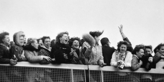 NEW YORK - FEBRUARY 7: Fans scream with excitement at the arrival of The Beatles at John F. Kennedy International Airport, Feb. 7, 1964. 