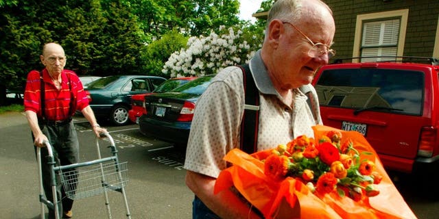Dr. Al Willeford (L) makes his way to a car as his friend, Dr. David Holmes (R), carries flowers that were given to Willeford during a news conference held by patient's advocacy group Compassion in Dying May 6, 2003 in Portland, Oregon.