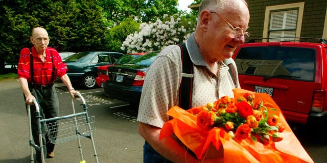 Dr. Al Willeford (L) makes his way to a car as his friend, Dr. David Holmes (R), carries flowers that were given to Willeford during a news conference held by patient's advocacy group Compassion in Dying May 6, 2003 in Portland, Oregon.