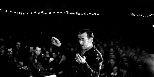 August 1944: Band leader Glenn Miller (1904-1944), conducting an ENSA concert during the Second World War. Original. 