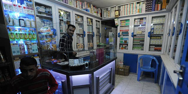 Two men mind a pharmacy as Afghans go about daily life on Nov. 10, 2015, in the northern city of Mazar-i-Sharif, Afghanistan.