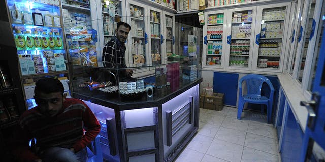 Two men tend to a pharmacy while Afghans go about their daily lives on November 11.  October 10, 2015 in the northern city of Mazar-i-Sharif, Afghanistan.