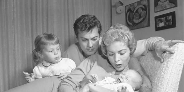 Janet Leigh holds Jamie Lee Curtis arsenic a babe arsenic Jamie's older sister Kelly, and dad, Tony Curtis, look on.