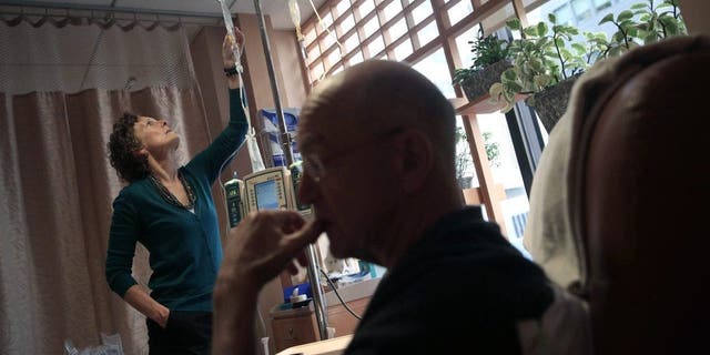 Youssef Cohen, 68, undergoes cancer treatment as his wife Lindsay Wright checks his medication drip on March 17, 2016 in New York City. Cohen has an incurable cancer called mesothelioma and is advocating for the right to choose how and when he will die, proposed in New York State's End of Life Options Act.