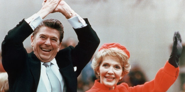 Ronald and Nancy Reagan waving and clasping hands in victory at Reagan's first inauguration, Jan. 20, 1981. 