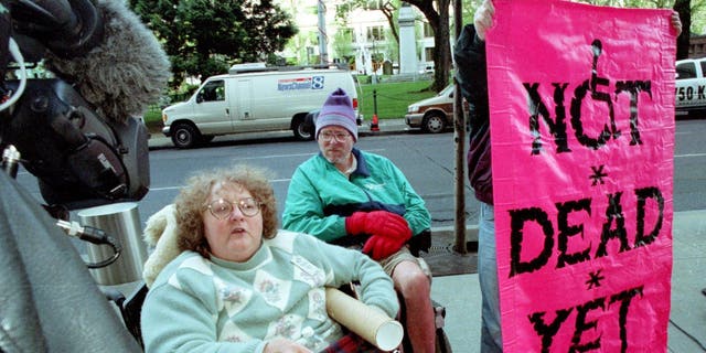 Ellie Jenny (L) and Brock Miller from the disability rights organization Not Dead Yet demonstrate against a federal judges ruling upholding physician-assisted suicide April 17, 2002, in Portland, OR.