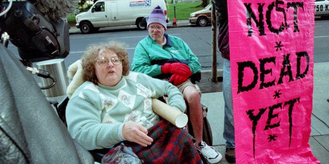 Ellie Jenny (L) and Brock Miller from the disability rights organization Not Dead Yet demonstrate against a federal judges ruling upholding physician-assisted suicide April 17, 2002, in Portland, OR.